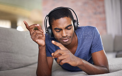 Buy stock photo Cropped shot of a handsome young man relaxing at home with some tunes
