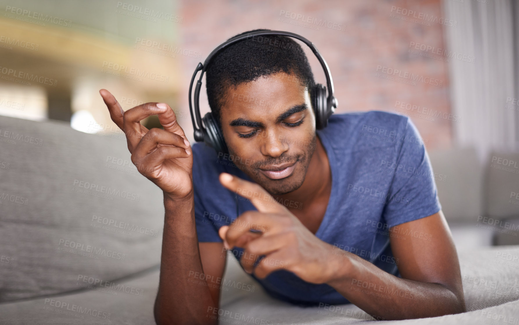 Buy stock photo Cropped shot of a handsome young man relaxing at home with some tunes