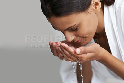 Buy stock photo Shot of a young woman washing her face at the basin