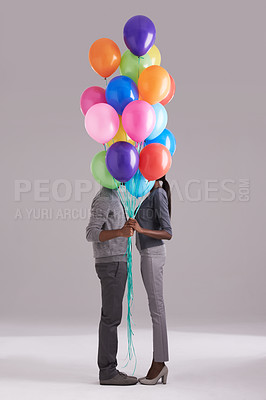 Buy stock photo Studio shot of a couple hiding behind a bunch of balloons