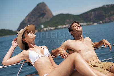 Buy stock photo Shot of an attractive young couple relaxing on a yacht together