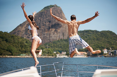 Buy stock photo Rear view of a young couple jumping off a yacht into the ocean