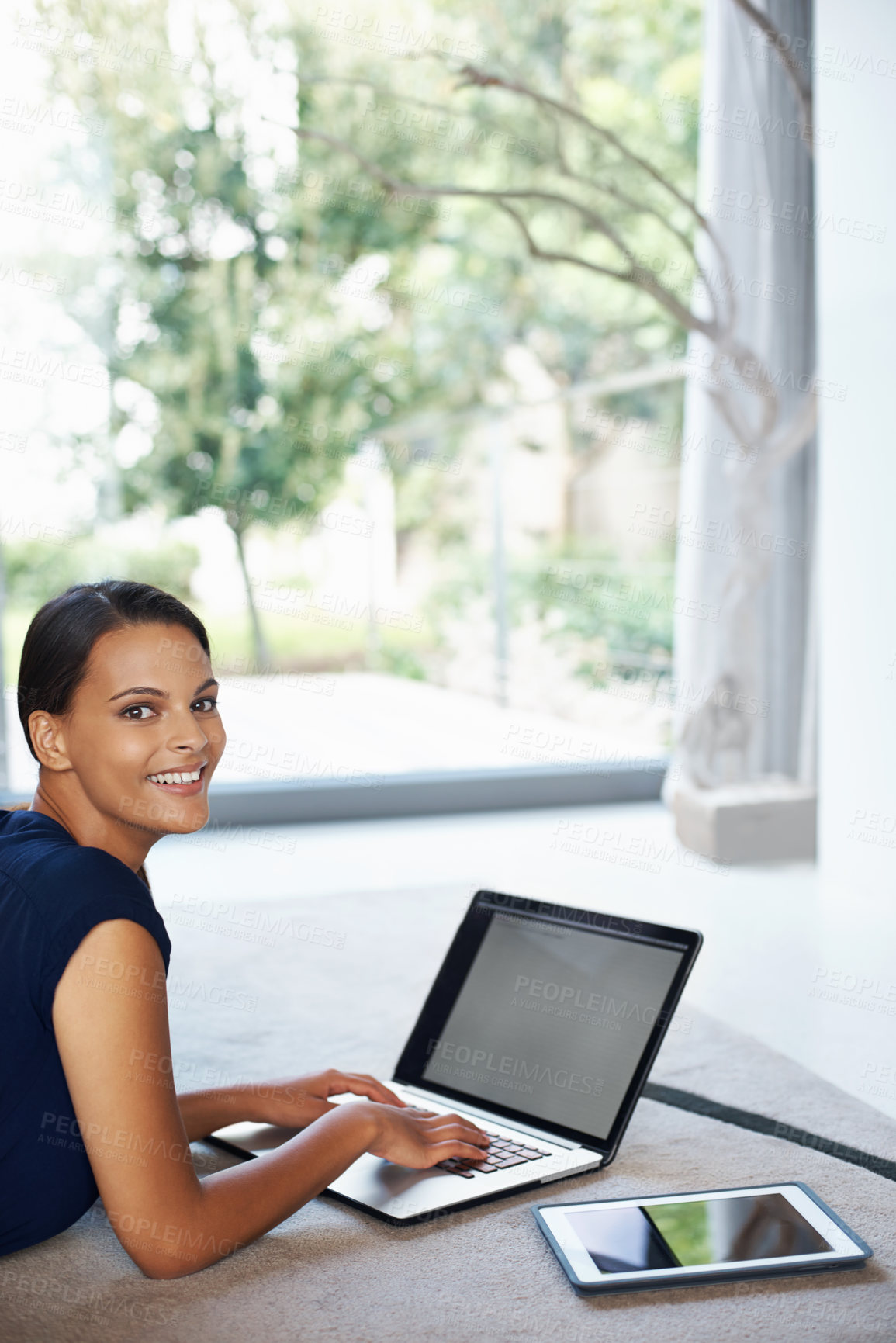 Buy stock photo Happy, computer and portrait of woman relaxing on carpet working on freelance project at home. Smile, technology and female person with laptop for creative research laying on floor mat in living room