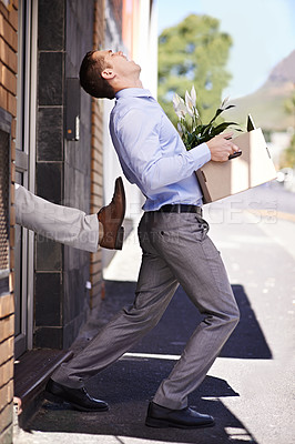 Buy stock photo Shot of a young businessman being kicked out of his office