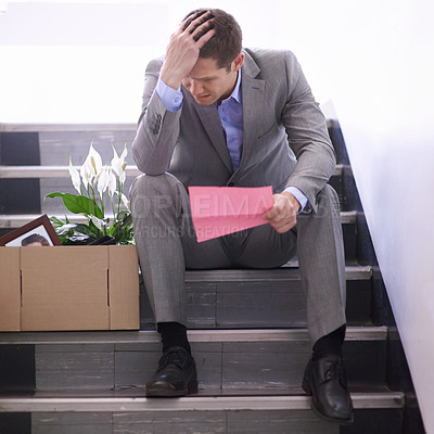 Buy stock photo Shot of a despondent businessman holding a pink slip terminating his employment