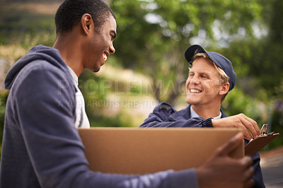 Buy stock photo Shot of a handsome young man giving a box to a courier