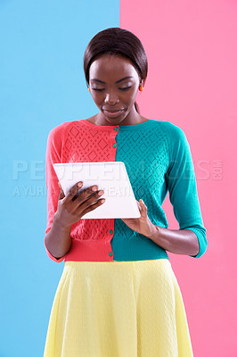 Buy stock photo Studio shot of a stylish young woman using a tablet aganst a colorful background