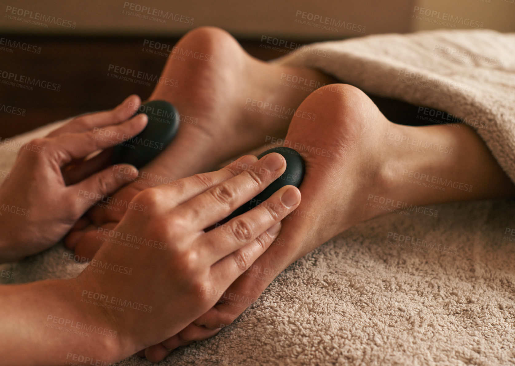 Buy stock photo Cropped shot of a woman receiving hot stone therapy on her feet