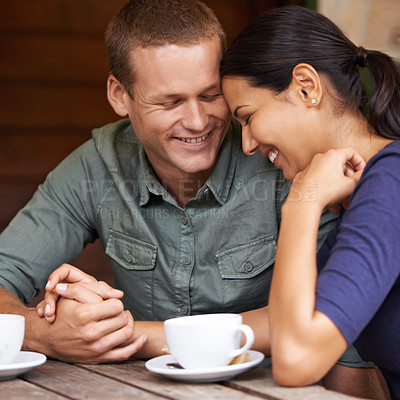 Buy stock photo A young multi-racial couple laughing together while drinking coffee at a cafe