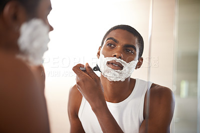 Buy stock photo A young man shaving in the mirror