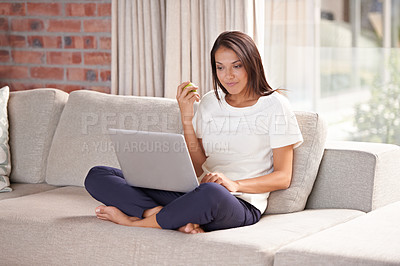 Buy stock photo Eating apple, laptop and woman on a home sofa reading email or streaming online. Female person relax on couch with fruit for remote work or study research on health blog for wellness or diet plan