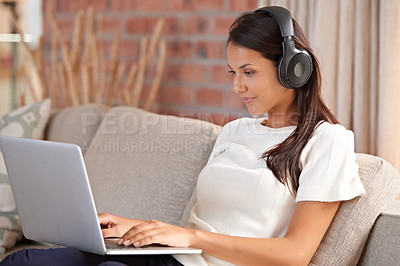 Buy stock photo Headphones, home and a woman typing on laptop on home sofa listening to music or streaming movies. Calm female person relax on couch to listen to radio or learning a language with internet connection