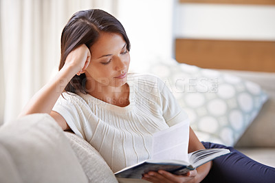 Buy stock photo Woman, sofa and reading with book in relax for story, literature or leisure in living room at home. Female person sitting on couch with novel for knowledge, education or learning in lounge at house