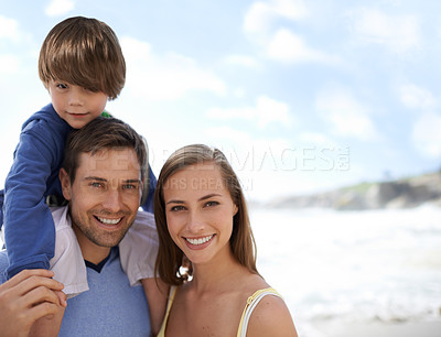 Buy stock photo Happy family, portrait and blue sky at beach on travel, holiday or vacation in summer with a smile. Man, woman and child together on adventure or quality time at sea with happiness, love and care
