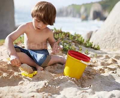 Buy stock photo Sand castle, beach and child with bucket and toys on summer holiday, vacation and relax by ocean. Childhood, building or digging and young boy playing for adventure,   fun and weekend by seaside