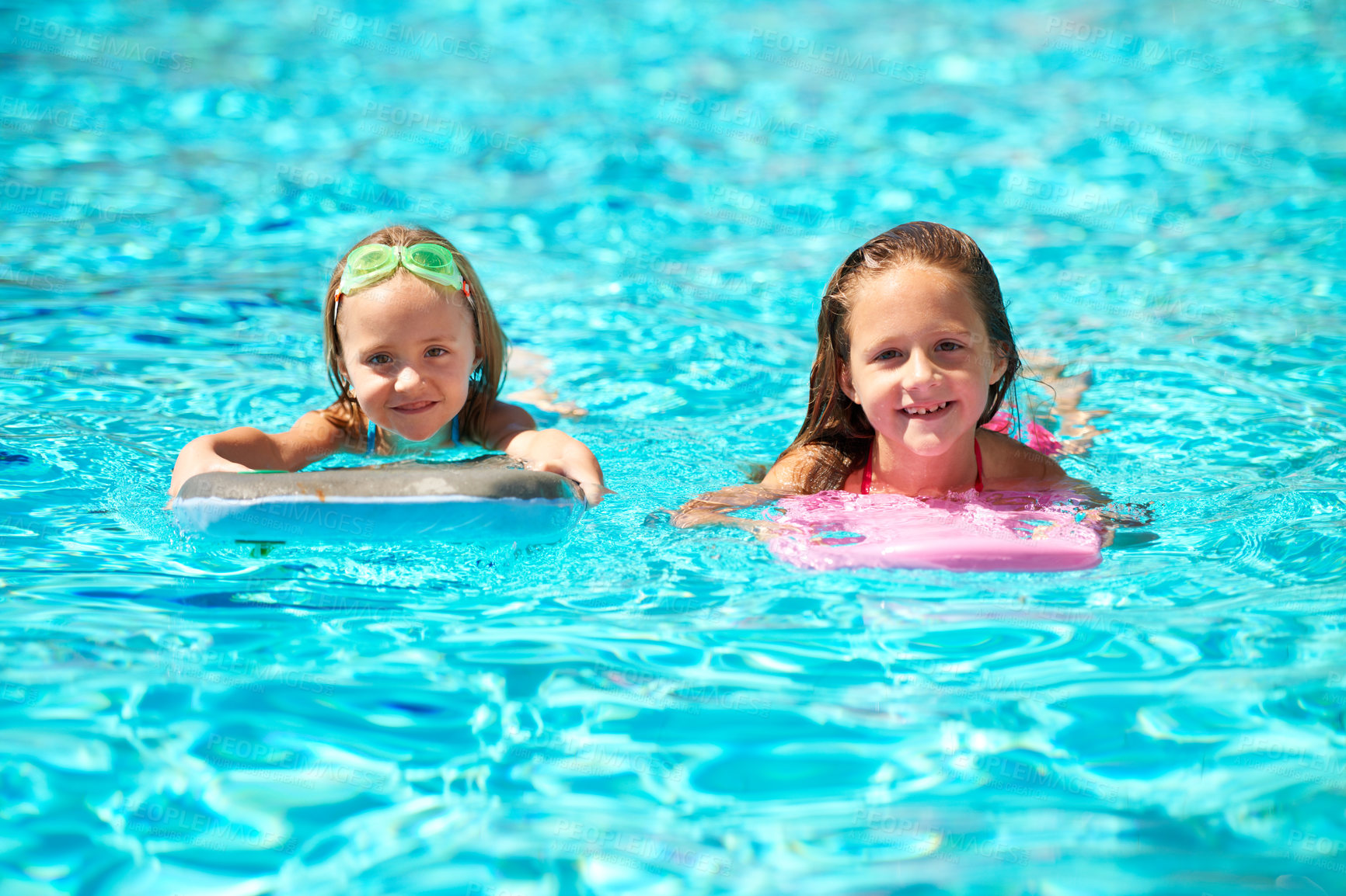 Buy stock photo Two little girls using pool inflatables while swimming