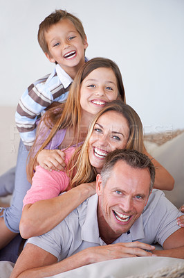 Buy stock photo Portrait of a happy young family of four piled on top of one another