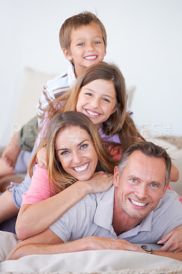 Buy stock photo Portrait of a happy young family of four piled on top of one another