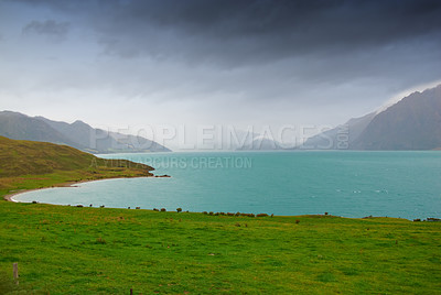 Buy stock photo Lake, mountains and nature with view of green scenery on foggy or misty morning outdoor in spring. Earth, sky and water with grass on ground in natural ecosystem or environment of New Zealand