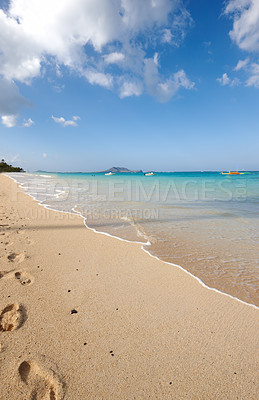 Buy stock photo Ocean, boat and blue sky for footprints, sand and rocks in shore for peace and tranquility. Seaside, waves and summer for vacation, location and beach for clear water on travel and tropical trip 