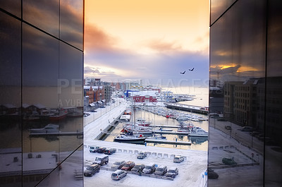 Buy stock photo A village or town in Bodo, Norway during sunset at a harbor with boats and yachts docked by a pier in the water. Two buildings create a frame for the view of the ocean during a snowy winter day