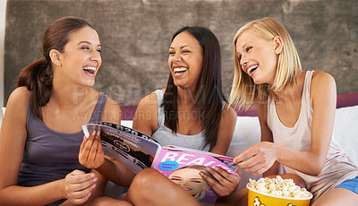 Buy stock photo Friends, laughing and magazine on bed with happiness, girls night and entertainment in home with popcorn. Women, paper and excited with snack in house for bonding, conversation and activity together