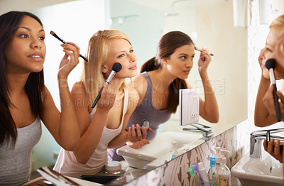 Buy stock photo Shot of three friends applying makeup in front of the mirror