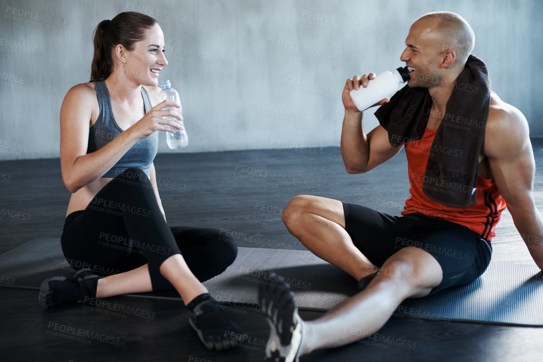 Buy stock photo Fitness, friends and relax on a gym floor for water, break and talking after cardio or routine. Active, people and woman with personal trainer relaxing after training, workout or physical exercise