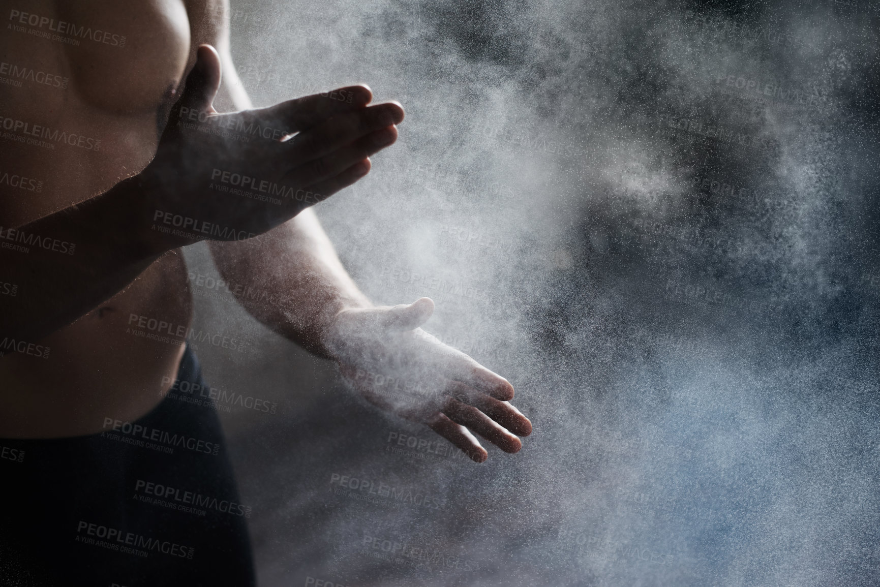 Buy stock photo A cropped view of a male gymnast dusting his hands with chalk