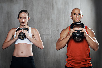 Buy stock photo A man and woman working out with kettle bells at the gym