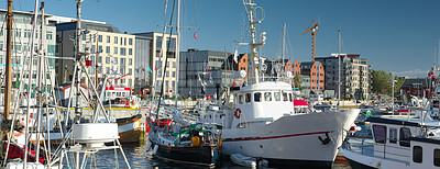 Buy stock photo A harbour with small boats on a sunny day. Many moored boats or yachts anchored in front of modern architecture buildings. Marina area or port of Bodo in Norway with urban cityscape in the background