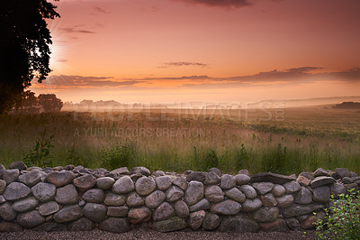 Buy stock photo A stone wall overlooking sunset over a Danish meadow