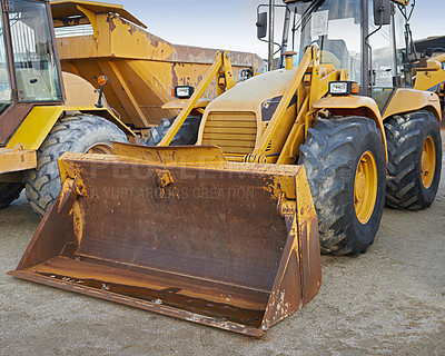 Buy stock photo Bulldozers at a construction site parked after operating. Huge orange powerful building vehicle with a hydraulic piston scoop and black wheels. Heavy machinery outside in an empty space