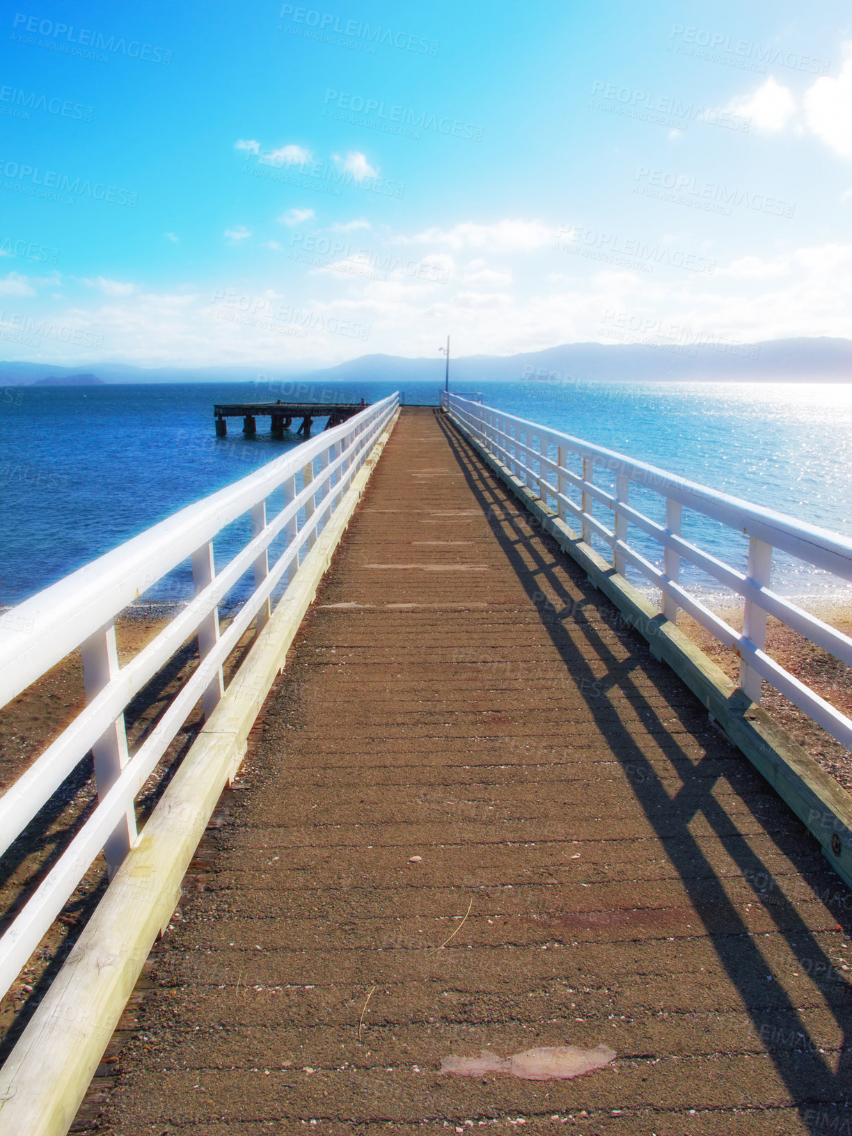 Buy stock photo Mountain, ocean and wooden pier on island with blue sky, tropical landscape and travel in Indonesia. Beach, vacation and relax on wood bridge, jetty or dock with sea water, clouds and summer in Bali