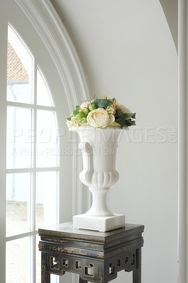 Buy stock photo Still life of a bouquet of fresh white roses arranged with fruit and green leaves. Fresh flowers decorated with apples in a white antique vintage style clay vase next to a window on an antique table