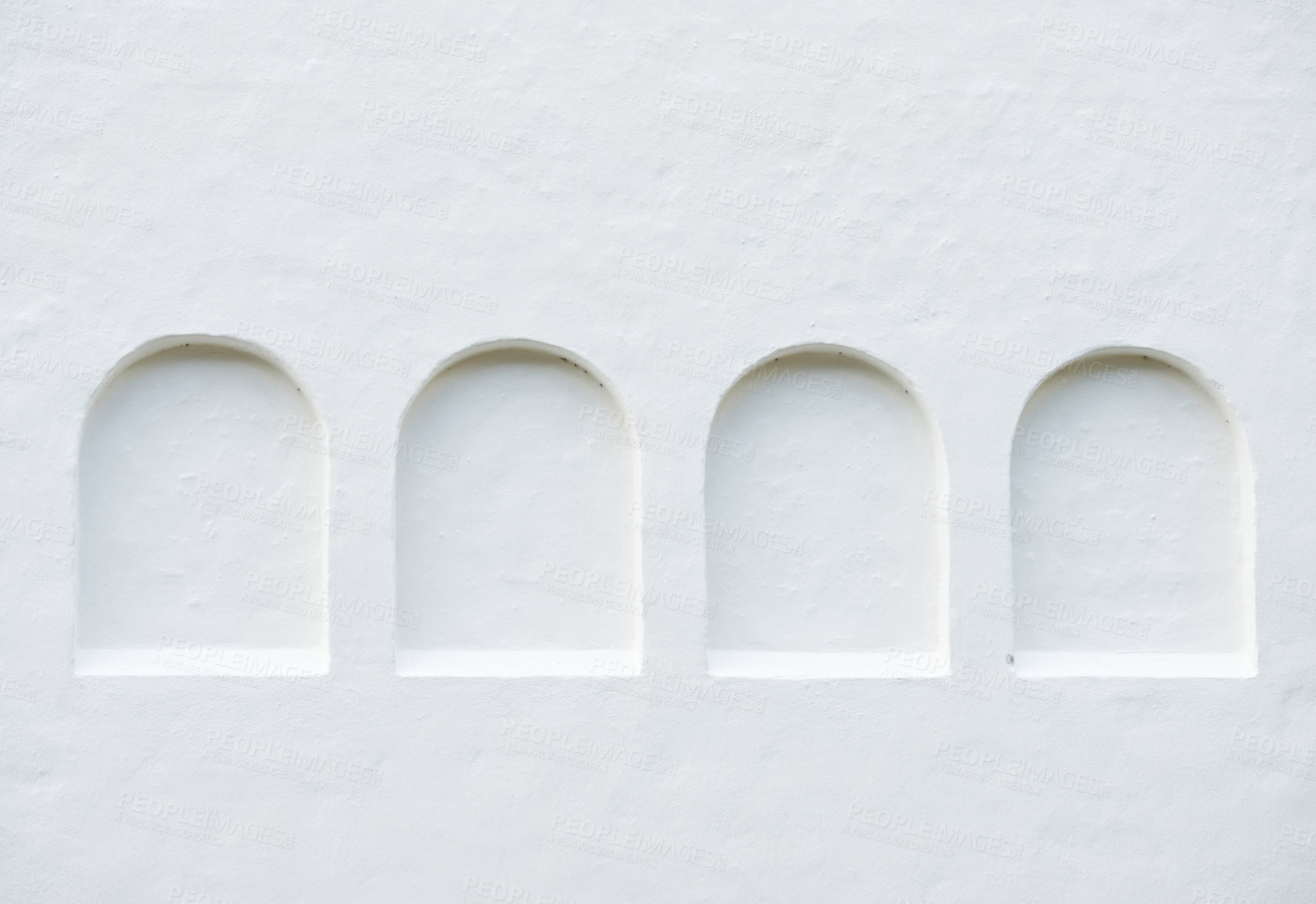 Buy stock photo White wall with arched indentations for copyspace concept. A row of four shallow recessed niches in the exterior wall of a building. Ancient architectural features on a painted stucco wall in Europe.