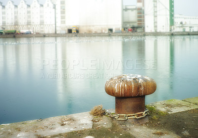 Buy stock photo Rusty mooring bollard cast iron at pier shore.A bollard port by a harbour. Sky and water background copyspace. Securing anchor point to prevent vessels from drifting away due tide, current and wind