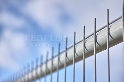 Buy stock photo Closeup of a new metal fence against a cloudy blue sky. Safety and security to protect your home and property. Sharp spikes to keep people out. Constructing a fence or cage. Danger keep out