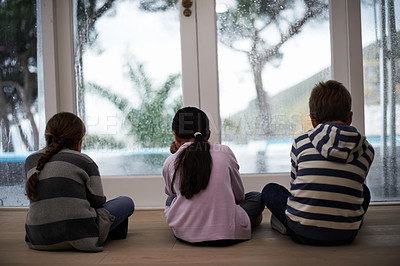 Buy stock photo Rain, window and sad child on a floor unhappy, upset or annoyed by bad weather at home. Glass, disappointed and sibling kids in a living room frustrated by storm, cold or unexpected winter disaster