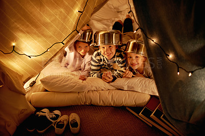 Buy stock photo Kids, portrait and siblings with pot helmet in a fort for fantasy, learning or playing in their home. Happy family, face and children on a floor with tent games, development or smile in a house
