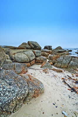 Buy stock photo Rocks, beach and shoreline with blue sky, sunshine and nature with environment and getaway trip. Stones, natural and seaside with fresh air and holiday in South Africa, travel and ocean with sand