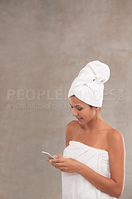 Buy stock photo A beautiful young woman in a towel texting in her bathroom