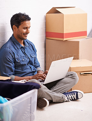 Buy stock photo A young man working on his laptop in between boxes