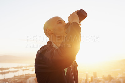 Buy stock photo Man, fitness and drinking water with sunset for natural sustainability, break or outdoor hydration. Thirsty male person or athlete with liquid bottle after workout, exercise or training in nature