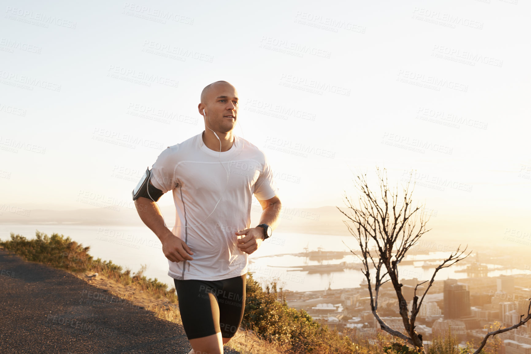 Buy stock photo Athlete, man and running in road with music for sport, exercise and fitness for competition or marathon in nature. Runner, person and workout with wellness, seaside and earphones for cardio in Mexico