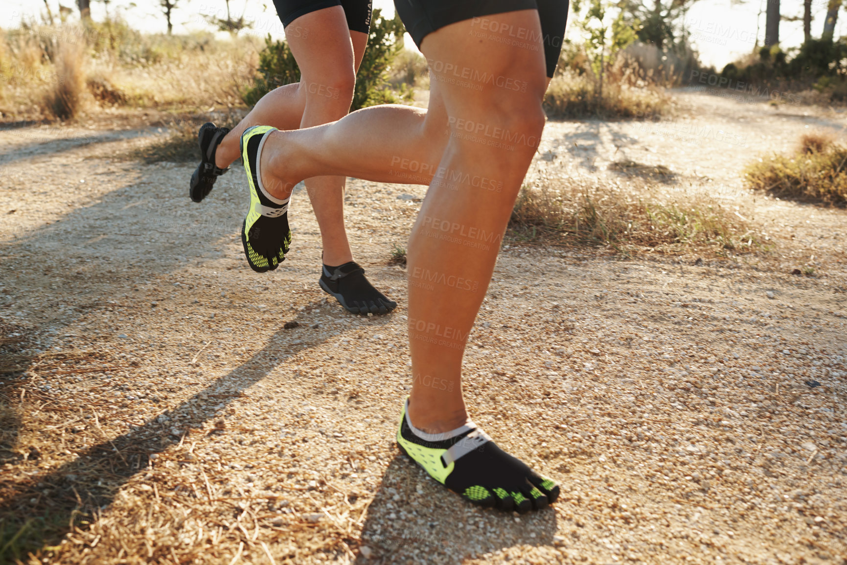 Buy stock photo Closeup, people and legs with running footwear for fitness, exercise or outdoor training on dirt road. Person and runner with sports shoes for hiking, trekking or cardio workout together in nature