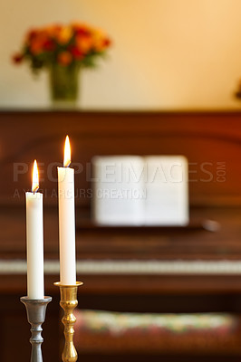 Buy stock photo Two thin candles in candle stick holders burning against blurry piano and bouquet of flowers background. Elegant candle lights in gold and silver holders, for a wedding, funeral home or church