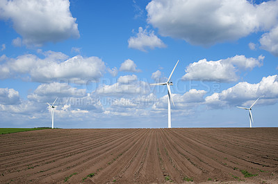 Buy stock photo Wind turbines and environmental infrastructure isolated against blue sky with copy space on an empty energy farm. Propellers converting sustainable energy into electric power in remote and rural area
