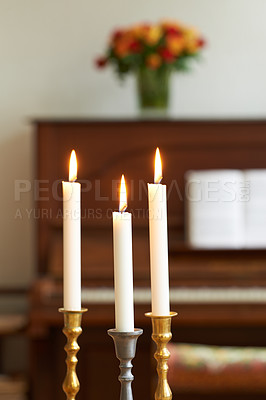 Buy stock photo Burning candles in a cosy room against a blurry background. Lighting a candle symbolizes hope and faith in religion. Candle lights in gold and silver holders, for a wedding, funeral home, or church