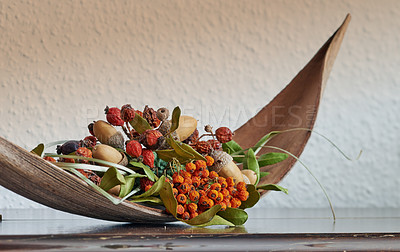 Buy stock photo Closeup of a bark basket with dried fruit, acorns and berries isolated on a wooden table with no people. Zoomed in on interior design centerpiece on a desk inside at home. Decorative nature decor